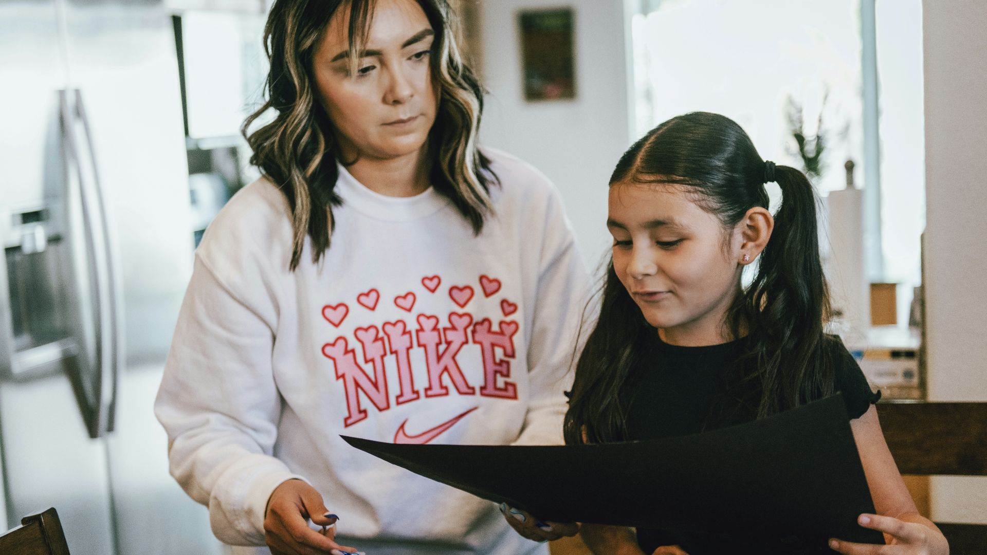 a woman standing next to a little girl in a kitchen