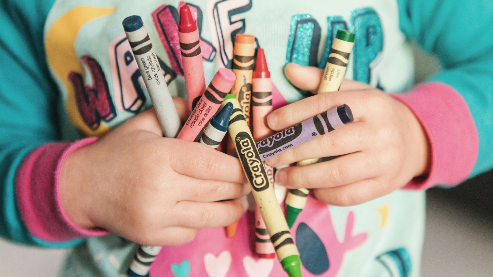 toddler holding assorted-color Crayola lot