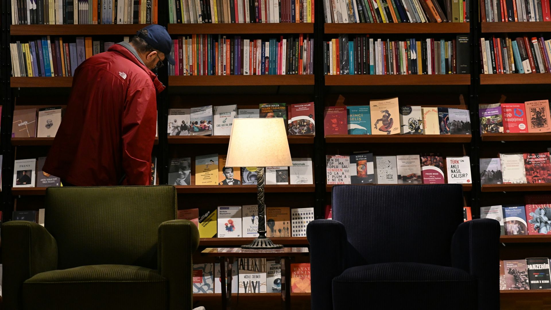 Man browsing books in a library with chairs and chairs.