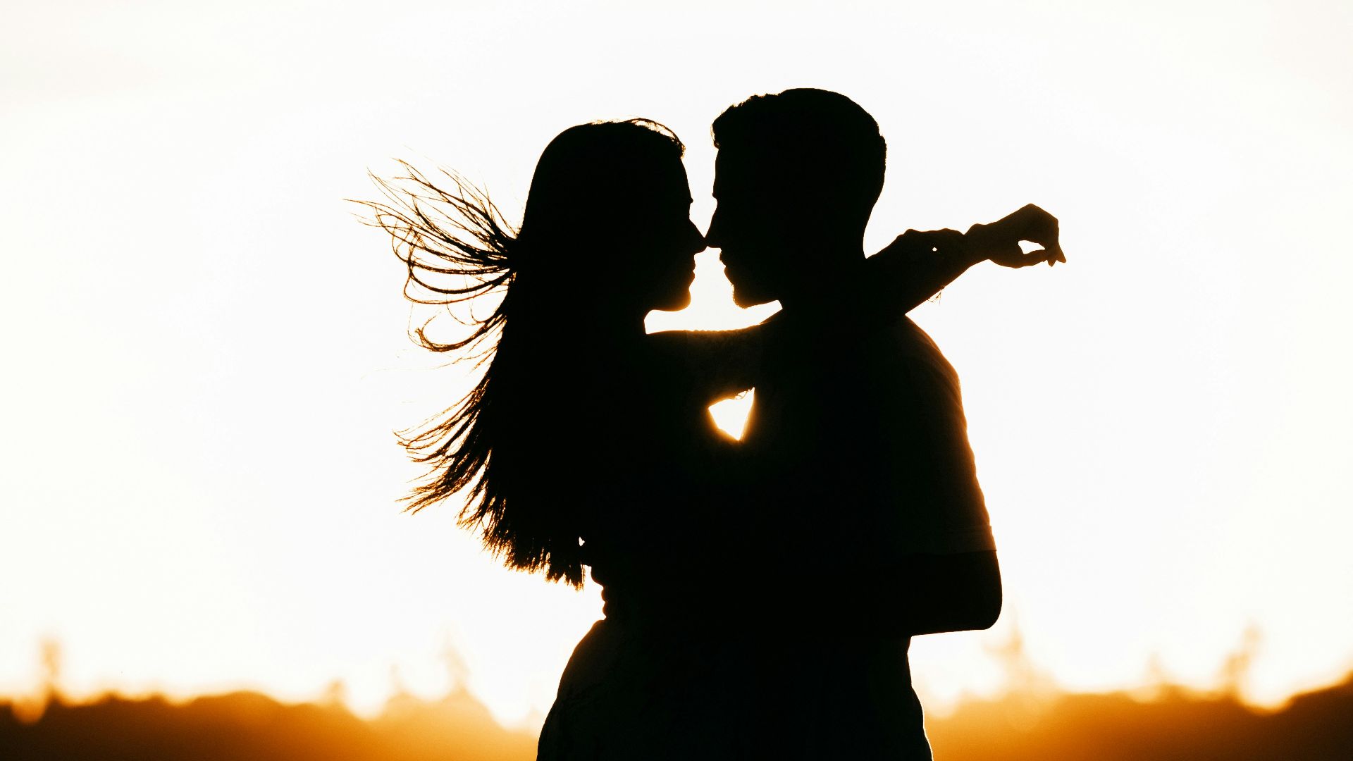 silhouette of woman standing on beach during sunset