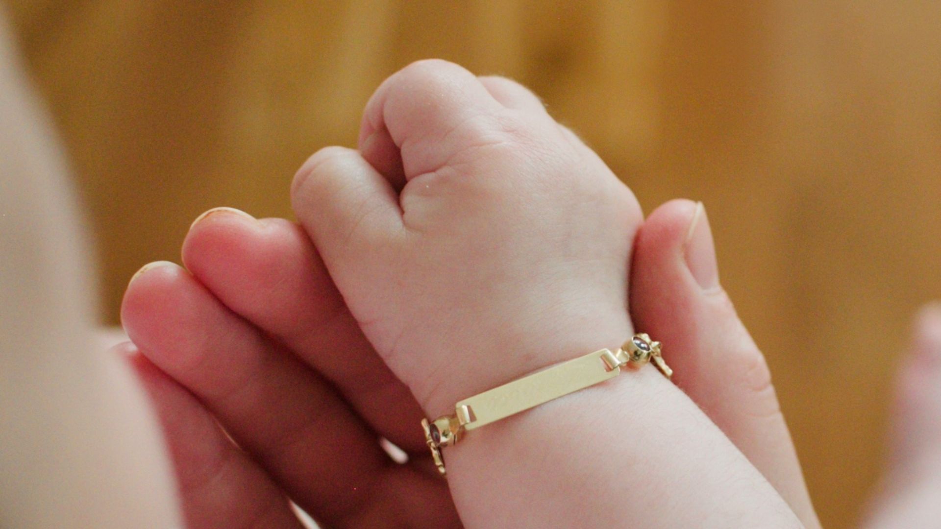 person wearing gold ring holding babys foot