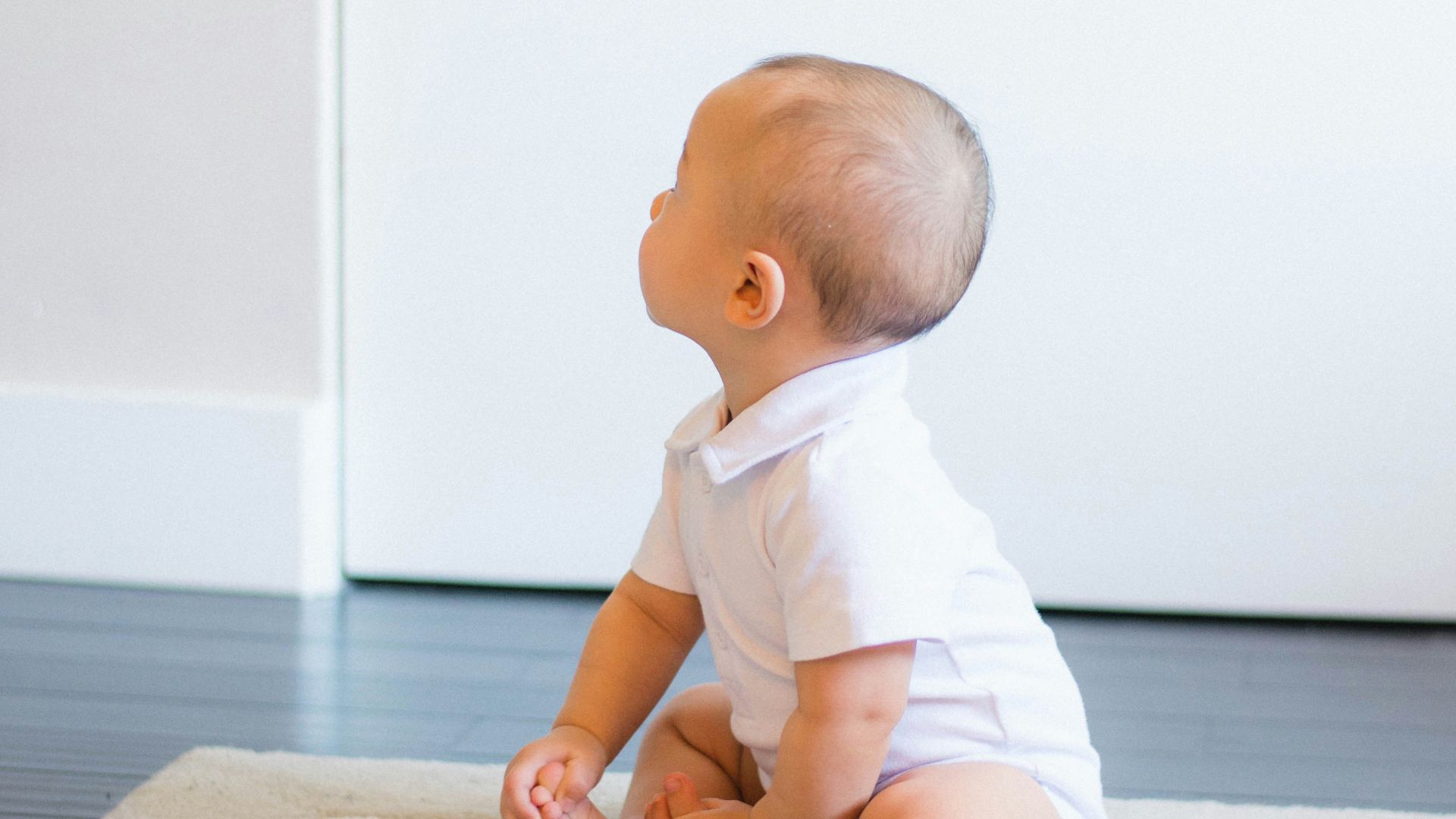 baby sitting on beige rug