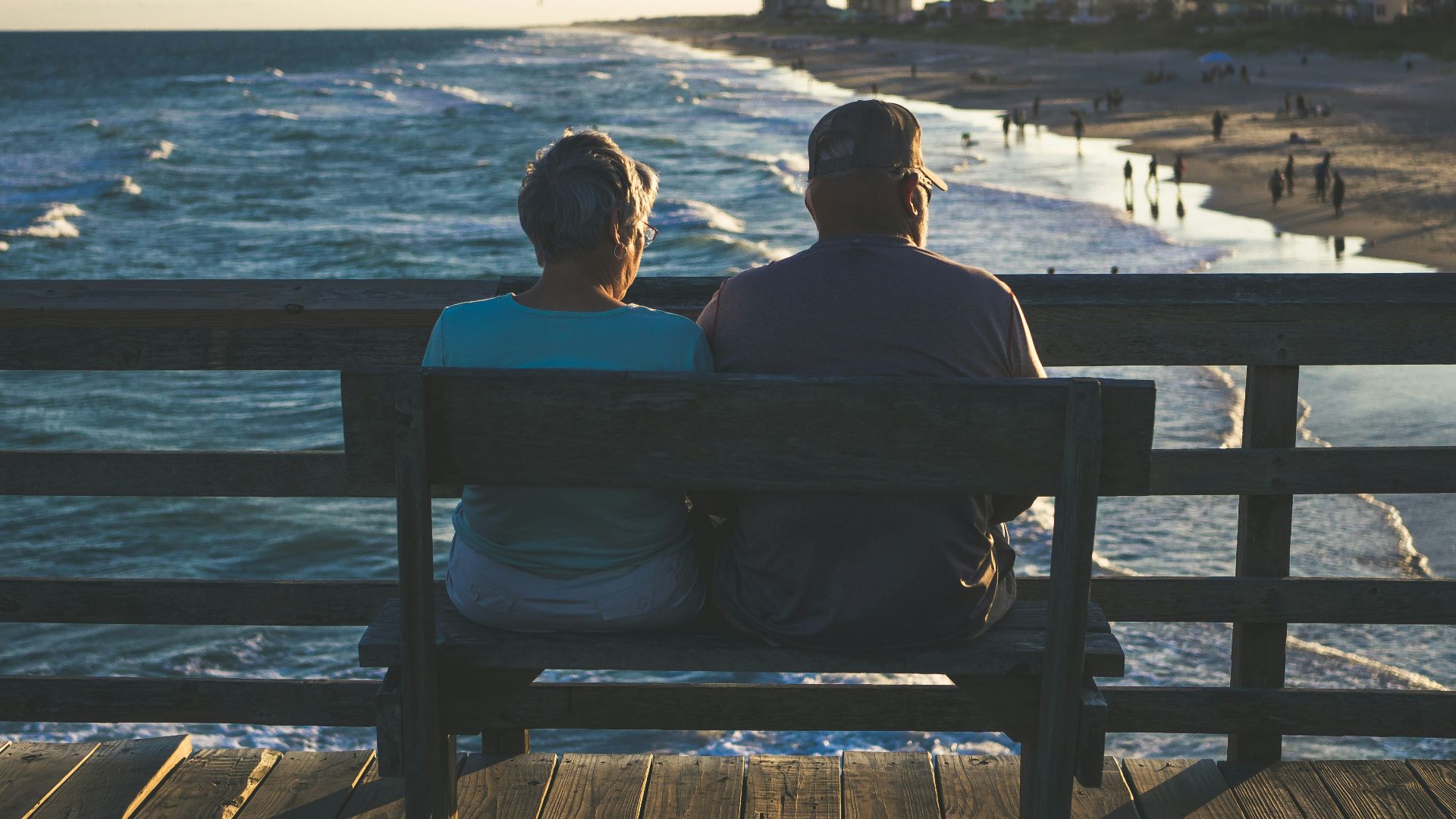 man and woman sitting on bench in front of beach