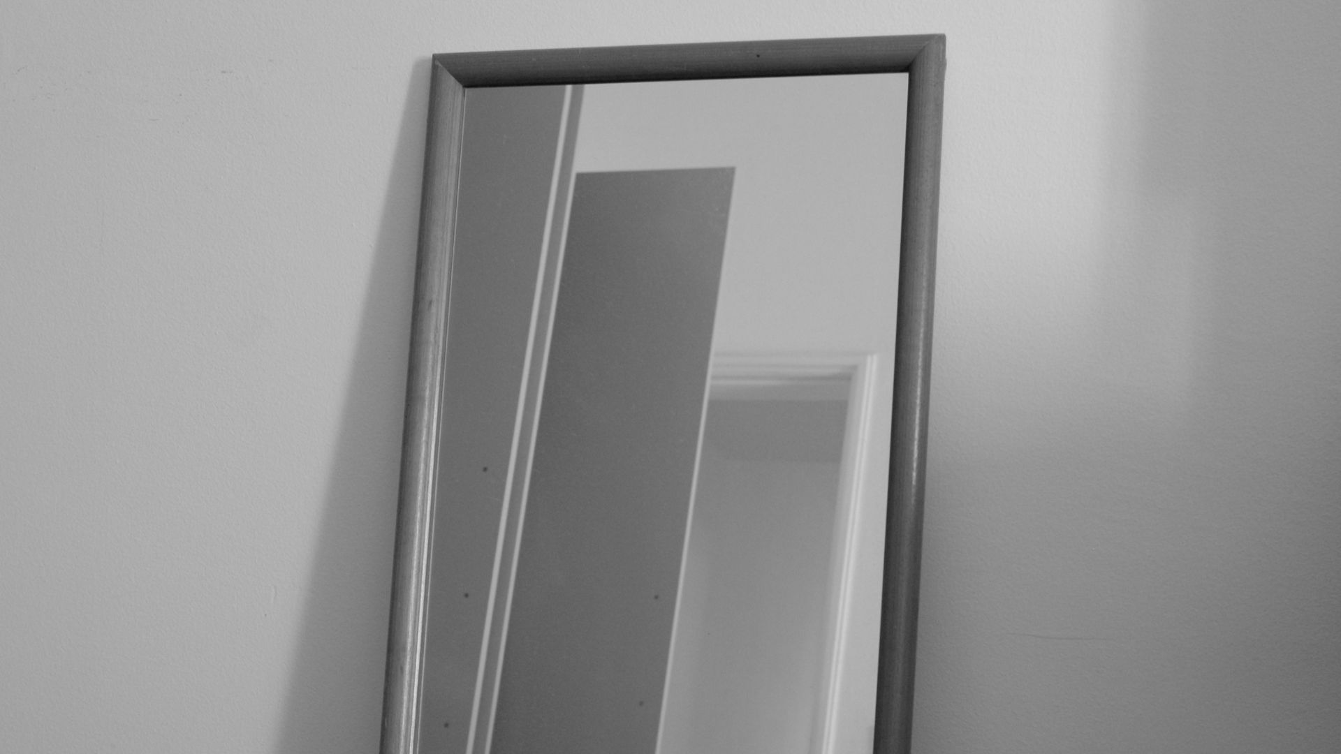 a black and white photo of a mirror on a wall
