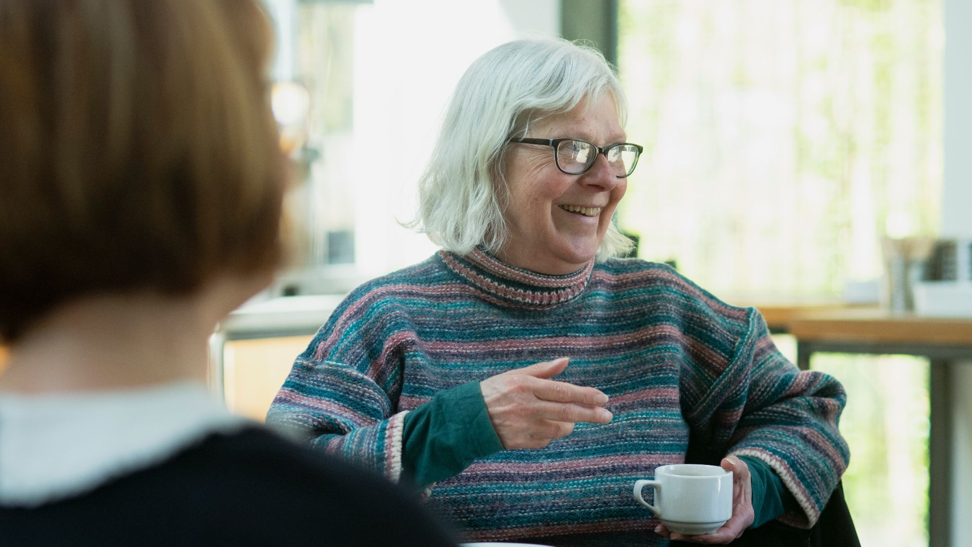 a woman sitting at a table talking to another woman