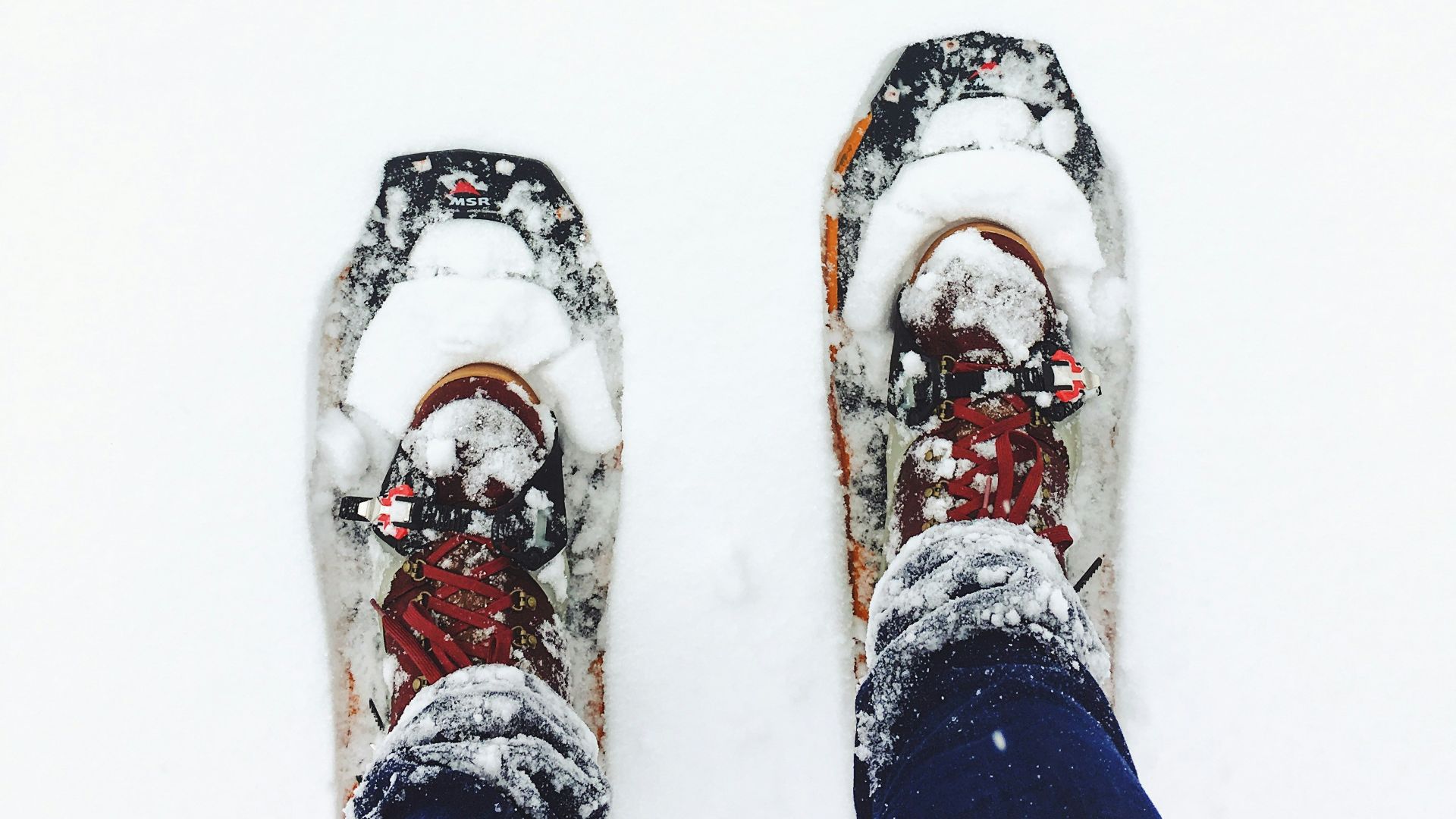 person wearing blue jeans standing on snow