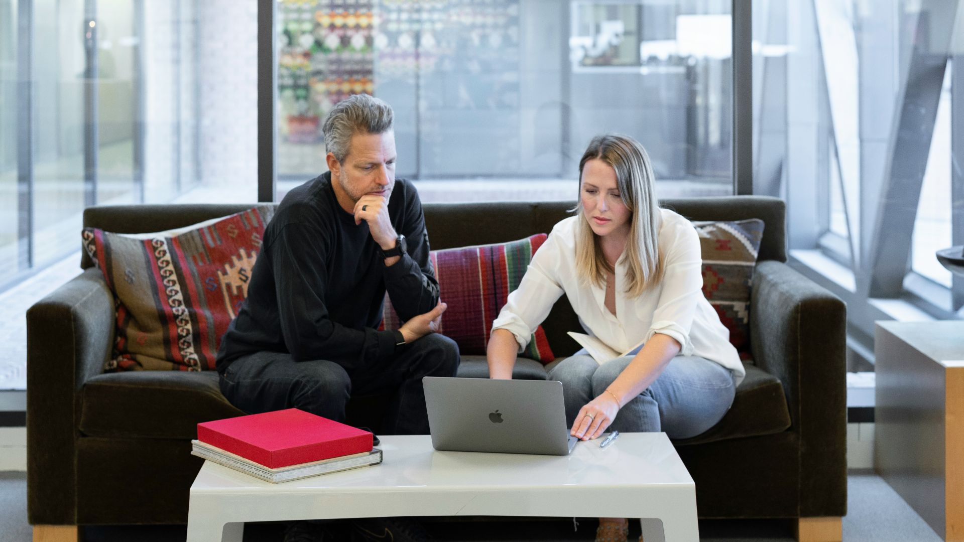man and woman sitting on couch using macbook