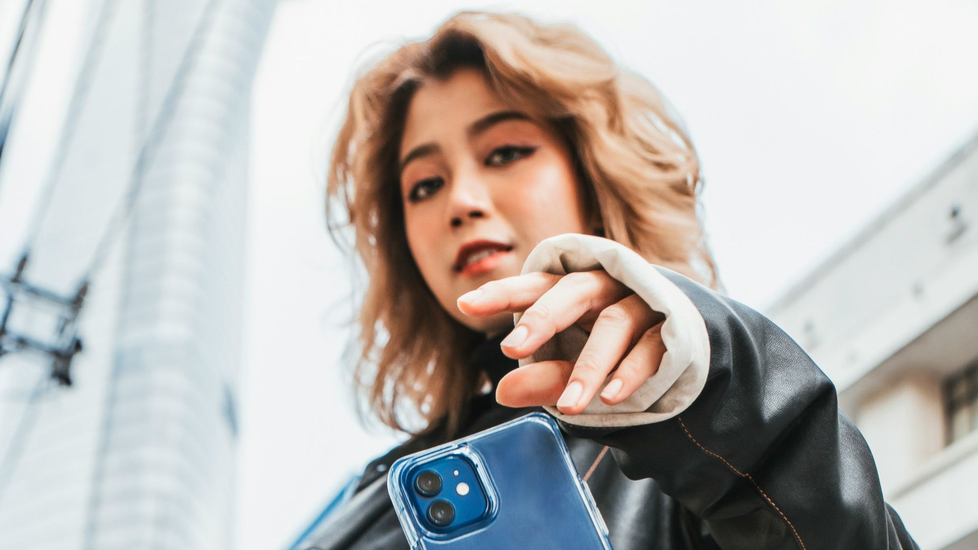 woman in black leather jacket holding blue iphone case