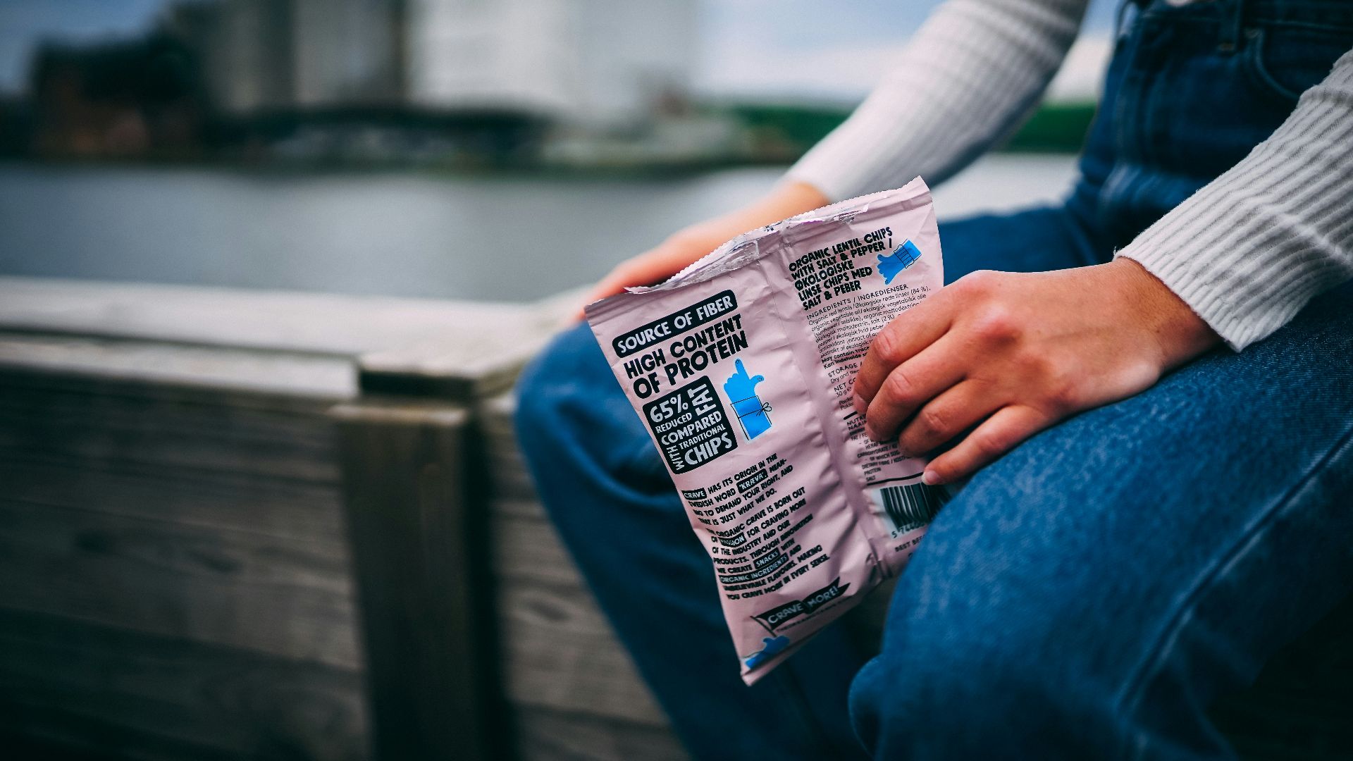 person holding white and blue plastic pack showing nutrition facts label