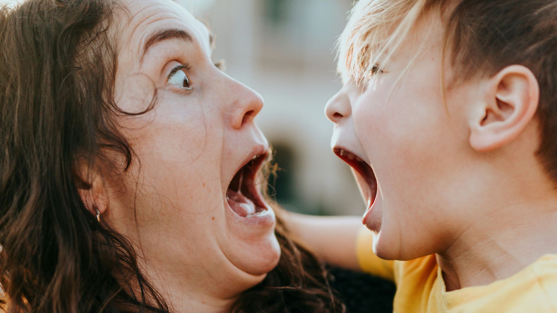 woman in black sweater kissing girl in yellow shirt