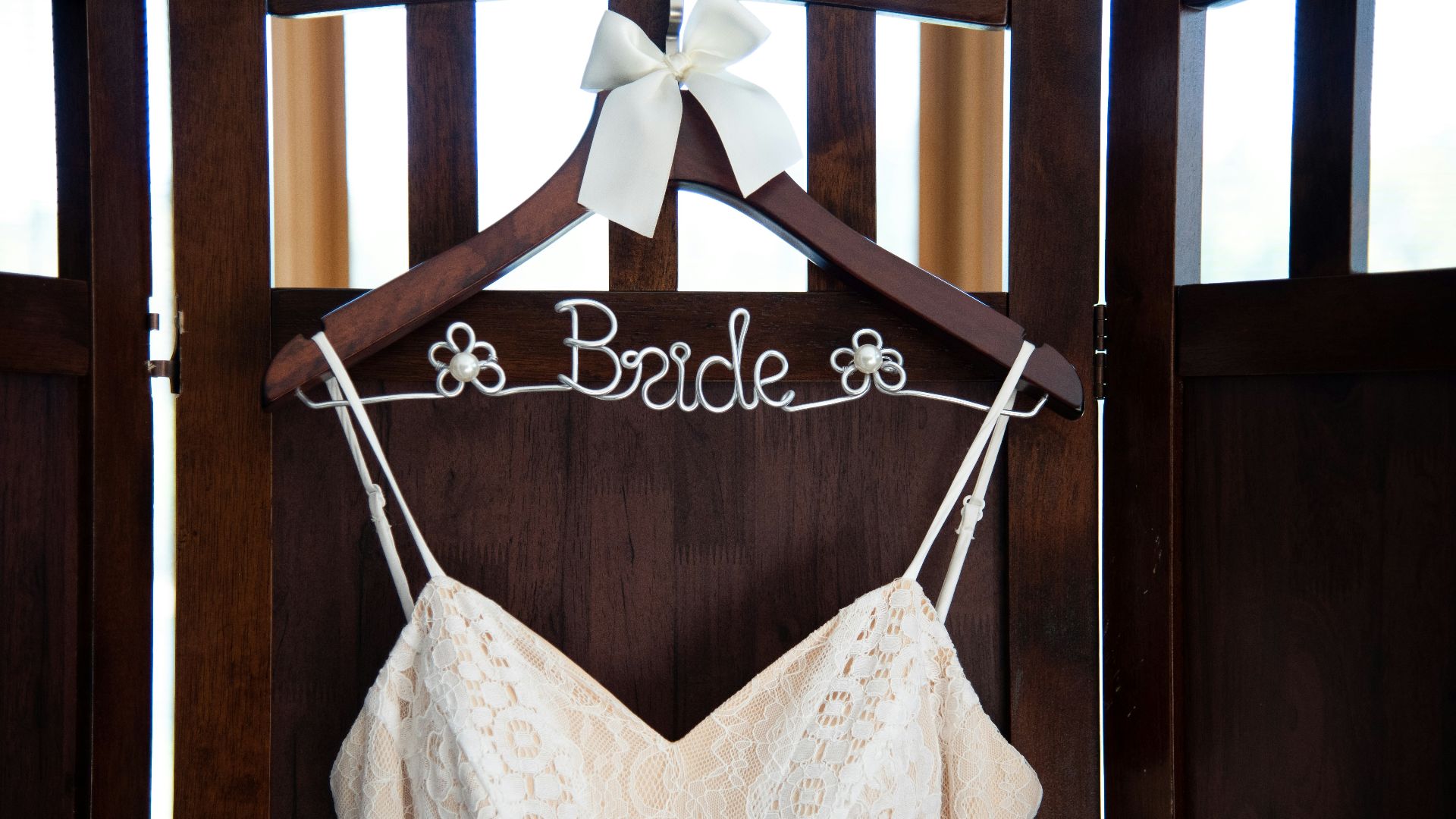 a wedding dress hanging on a wooden hanger