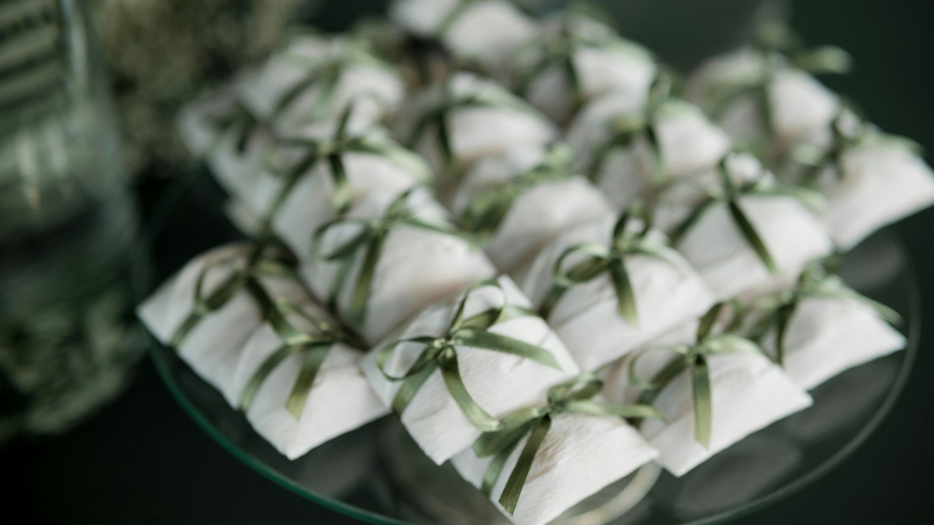 Small white gifts tied with green ribbon on a platter