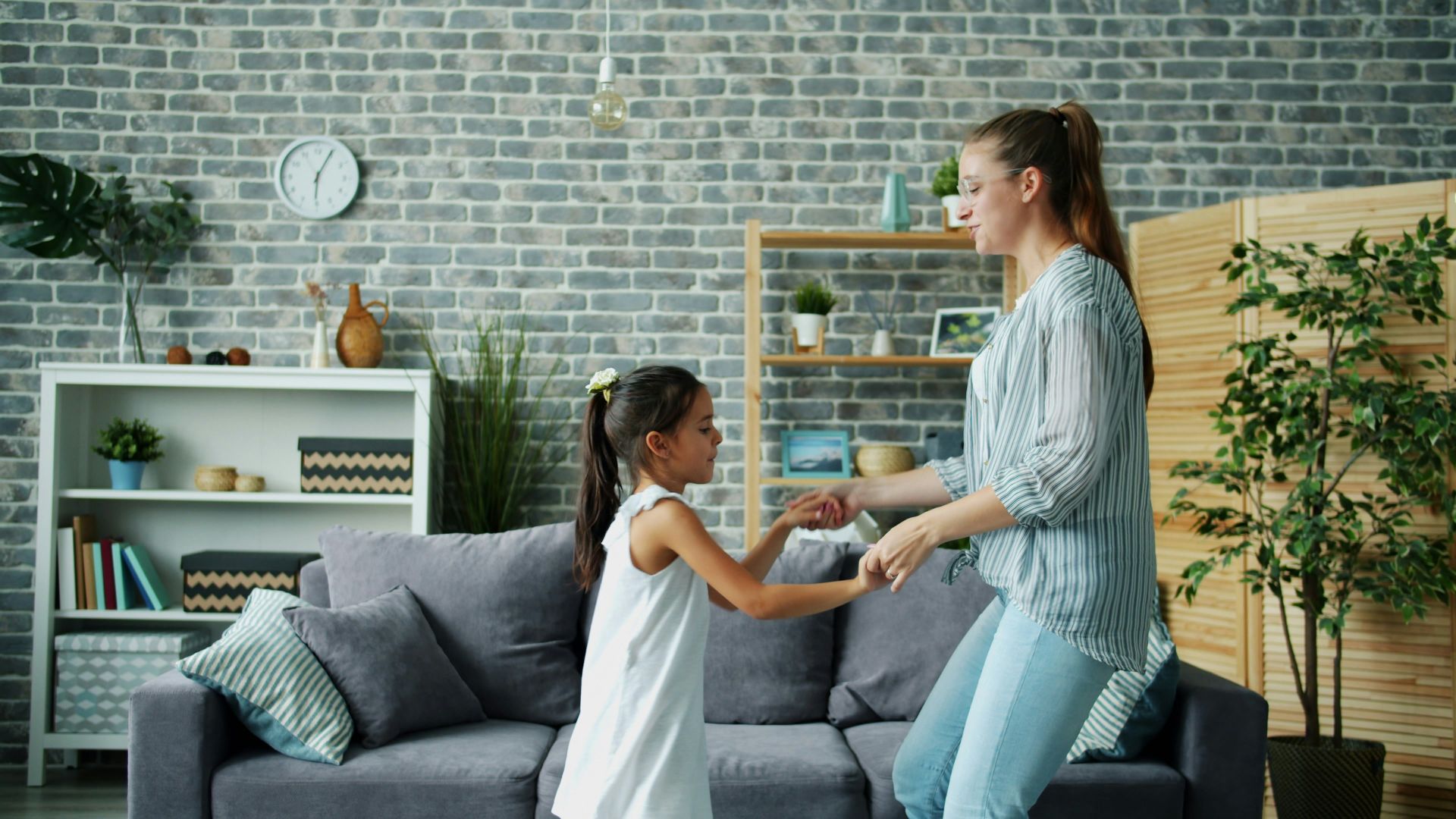 Mother and daughter dancing together in living room.