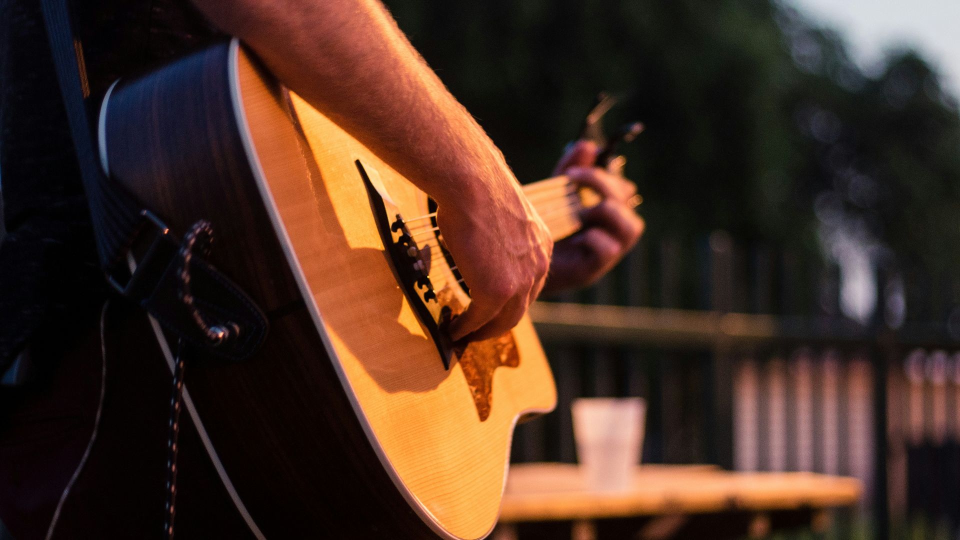 man in black t-shirt playing brown acoustic guitar