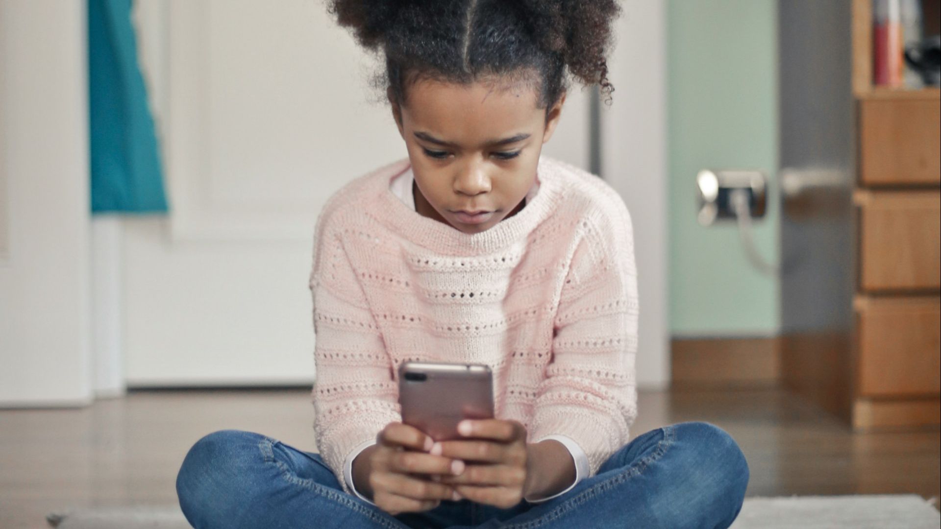 girl in white sweater and blue denim jeans sitting on floor