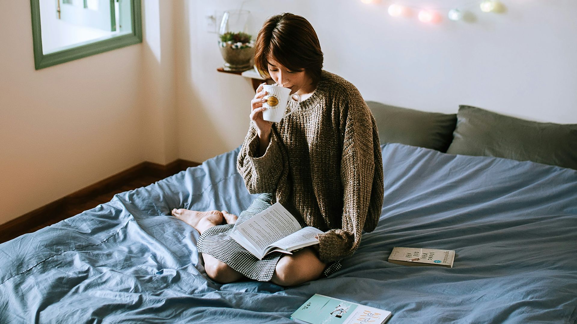 woman in gray sweater sitting on bed