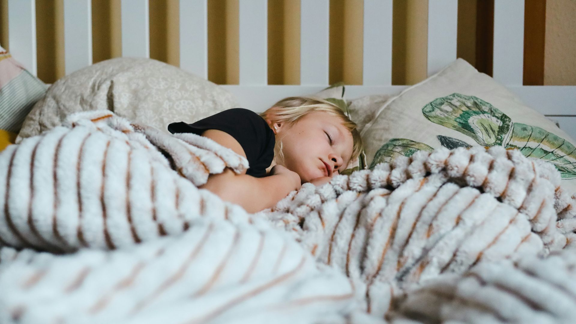 a little girl sleeping in a bed with a blanket