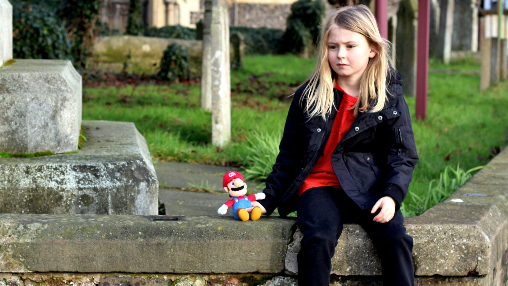 girl in black jacket sitting on concrete bench during daytime