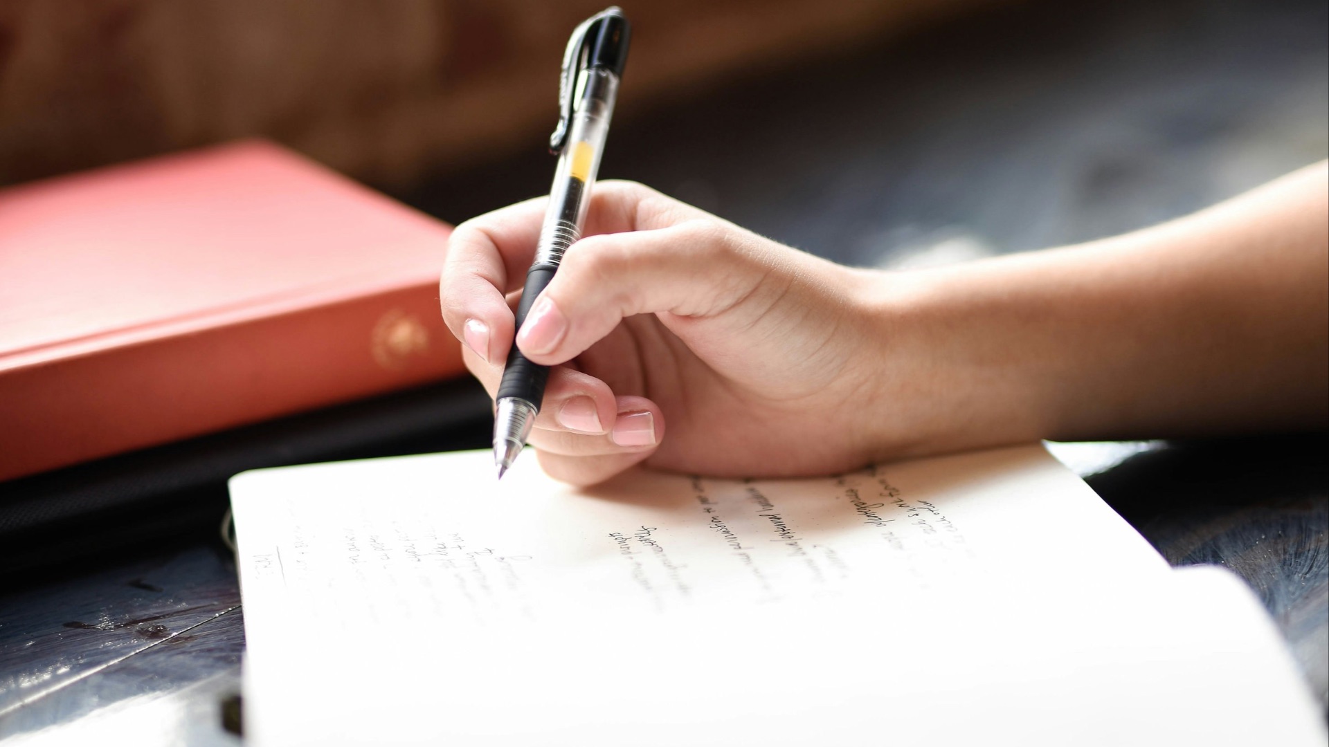 a person writing on a piece of paper with a pen