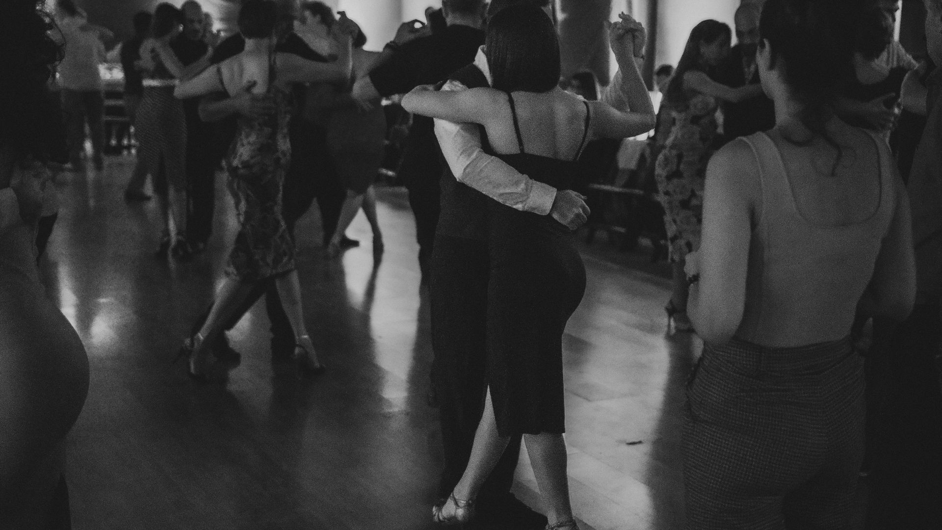 Couples dancing ballroom in a dimly lit room.