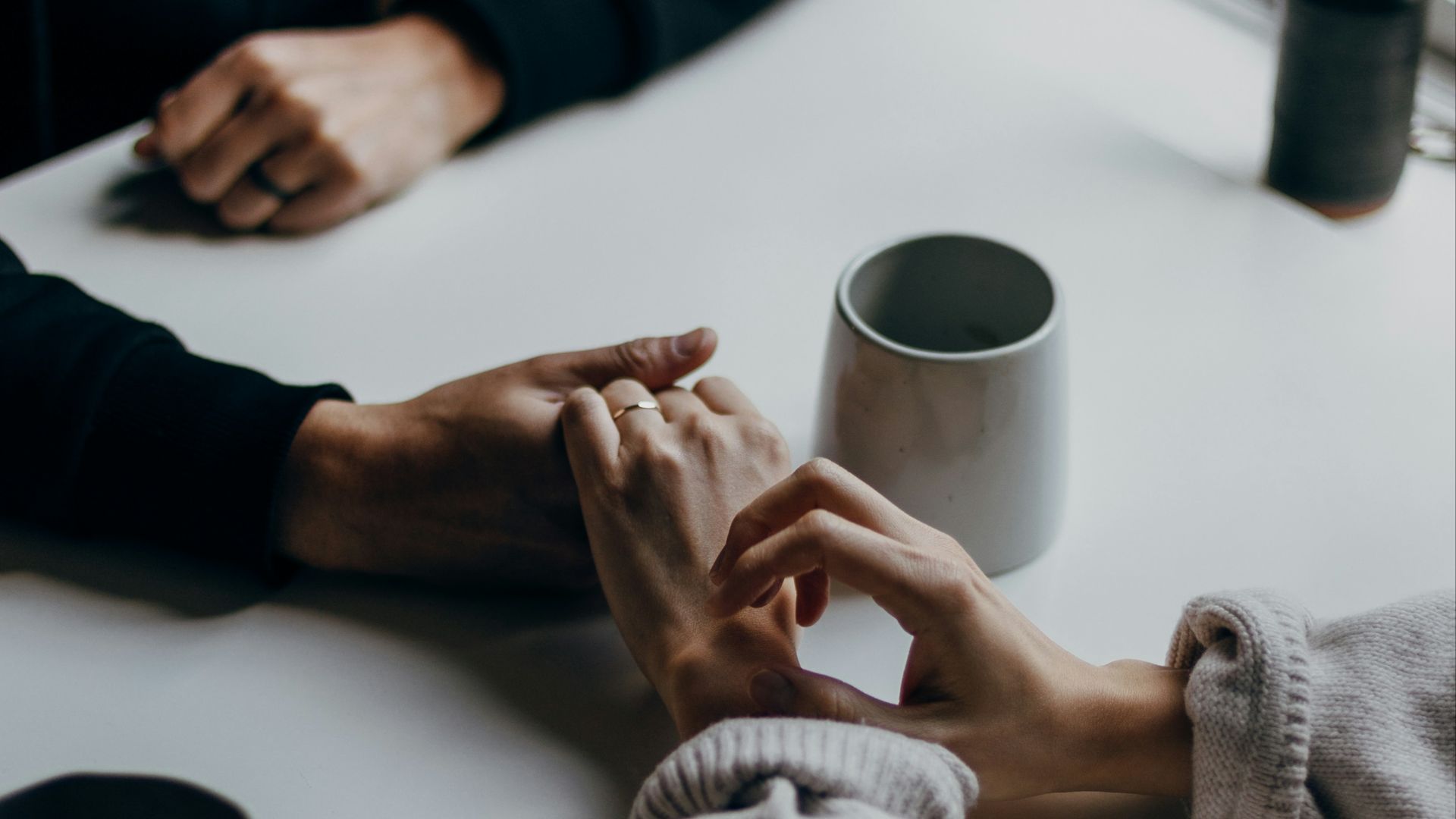person in black long sleeve shirt holding white ceramic mug