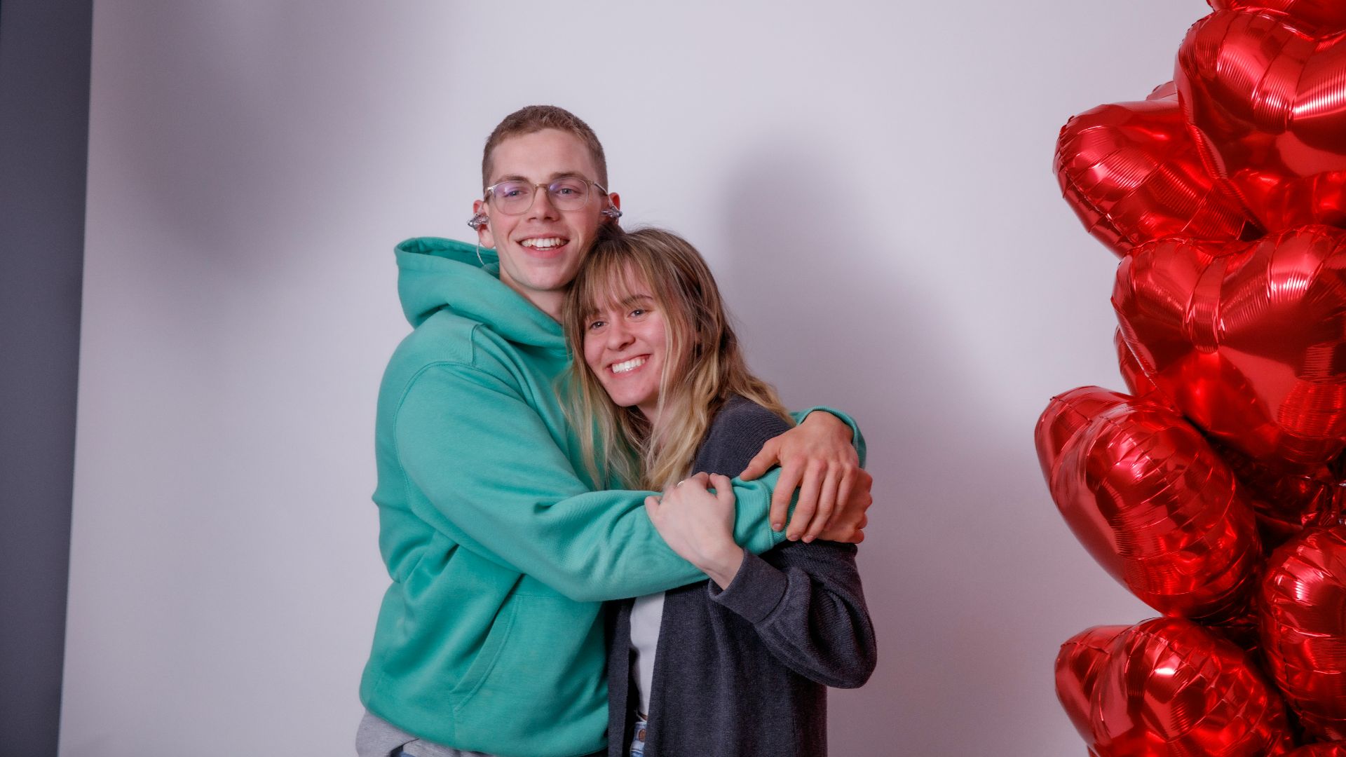 a man and a woman hugging in front of balloons