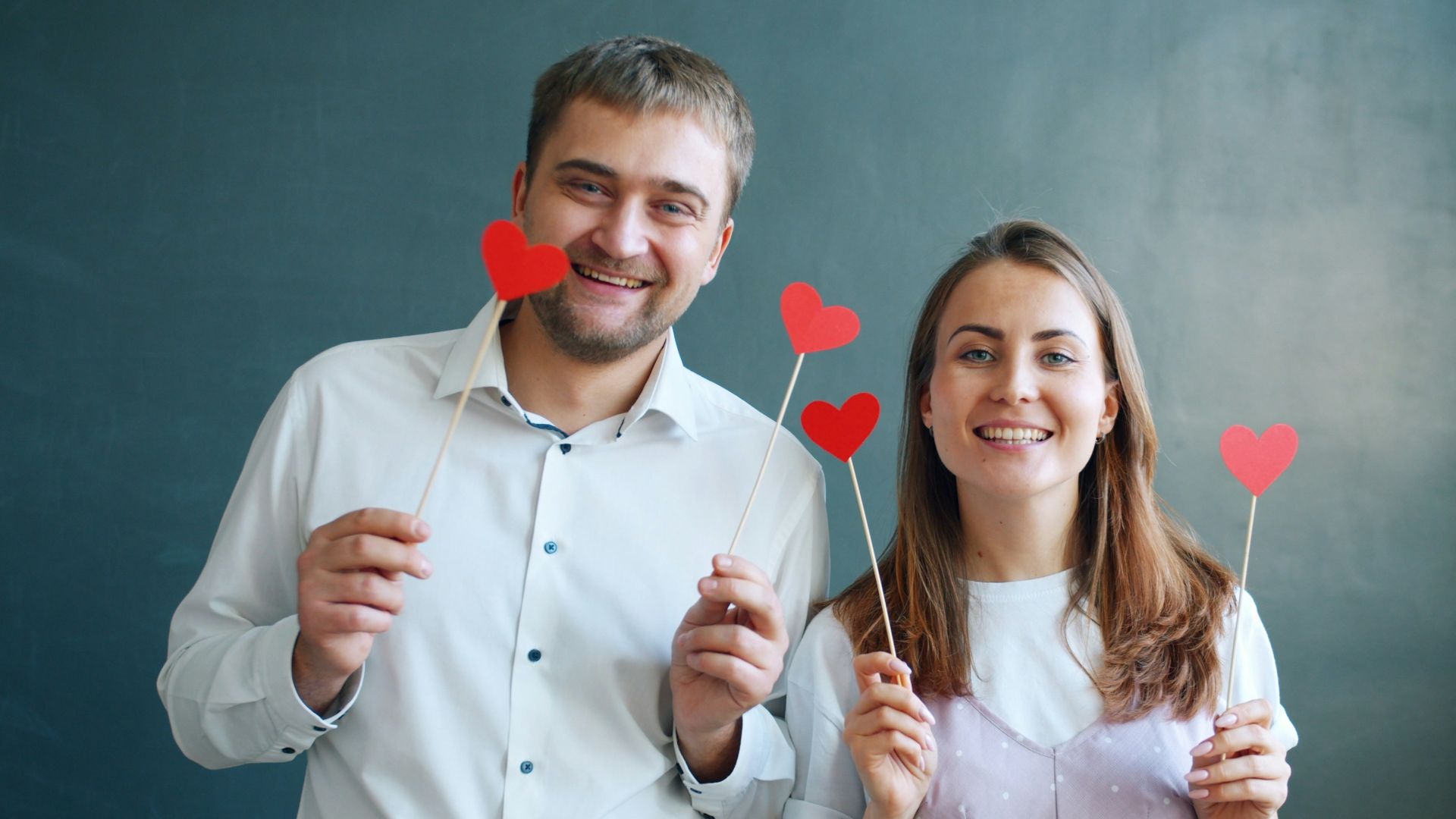 Couple holding red heart decorations