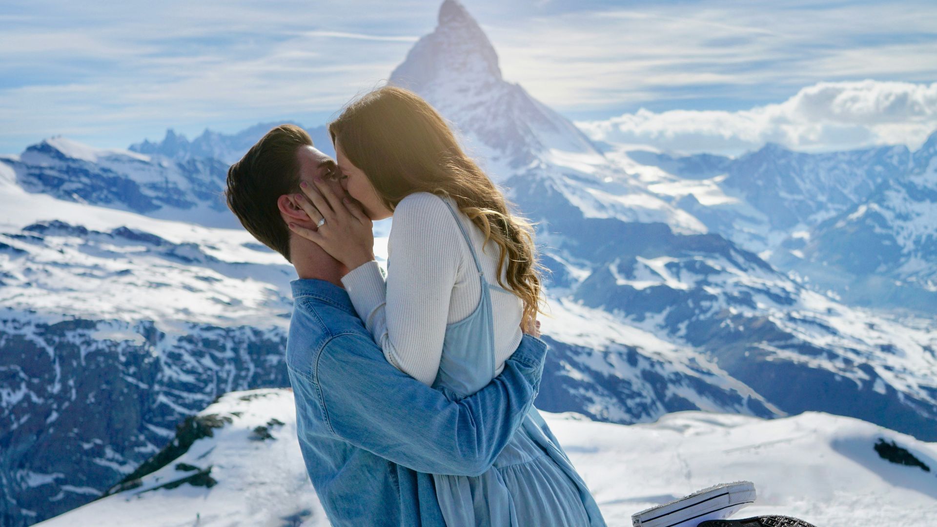 man carrying woman and kiss under clear blue sky