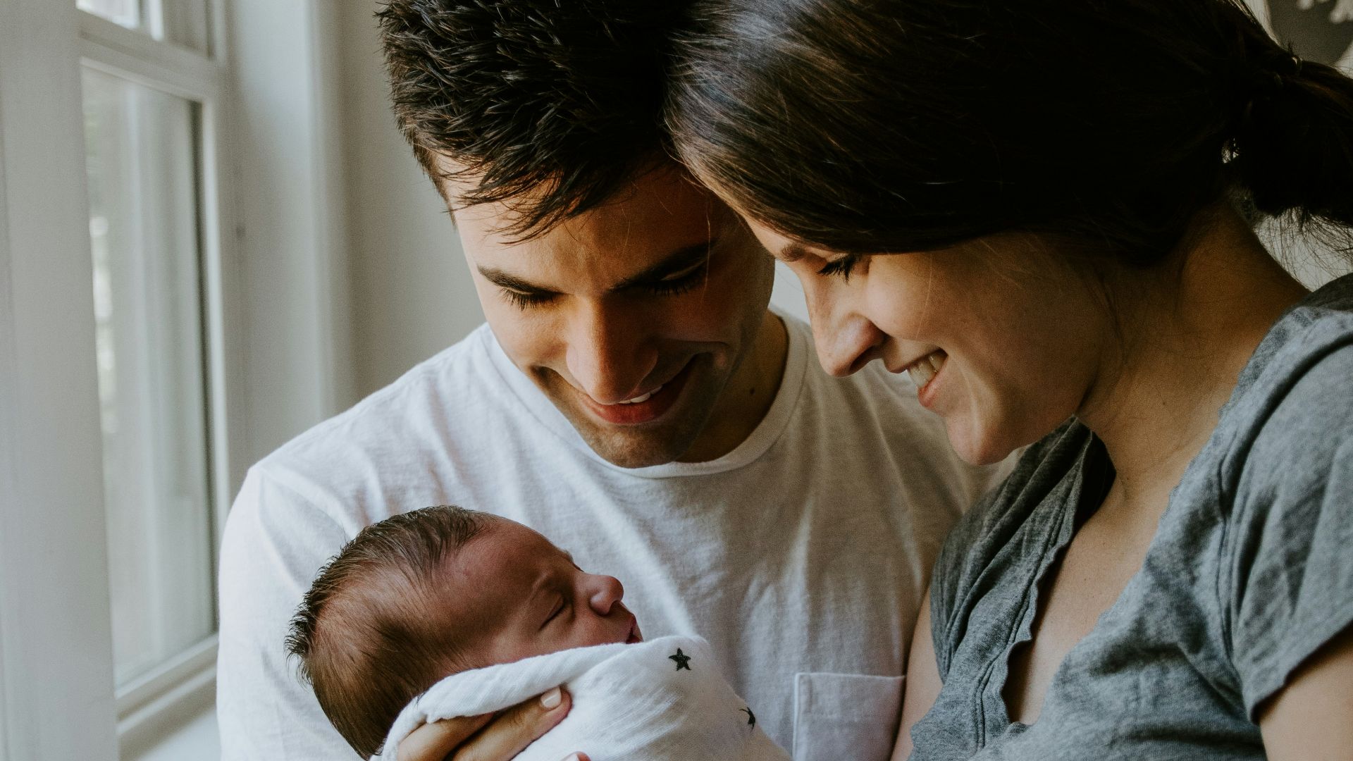 woman holding baby beside man smiling