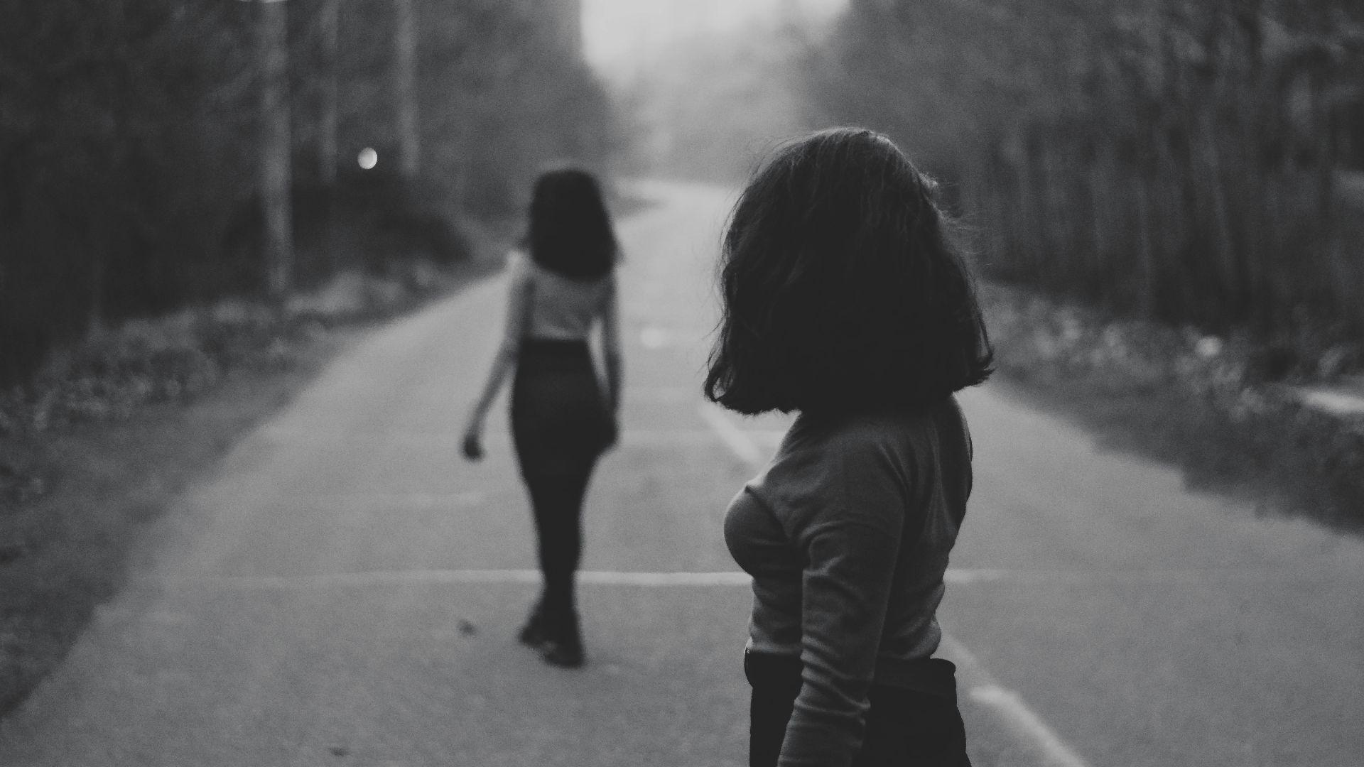 woman in black jacket walking on road during daytime