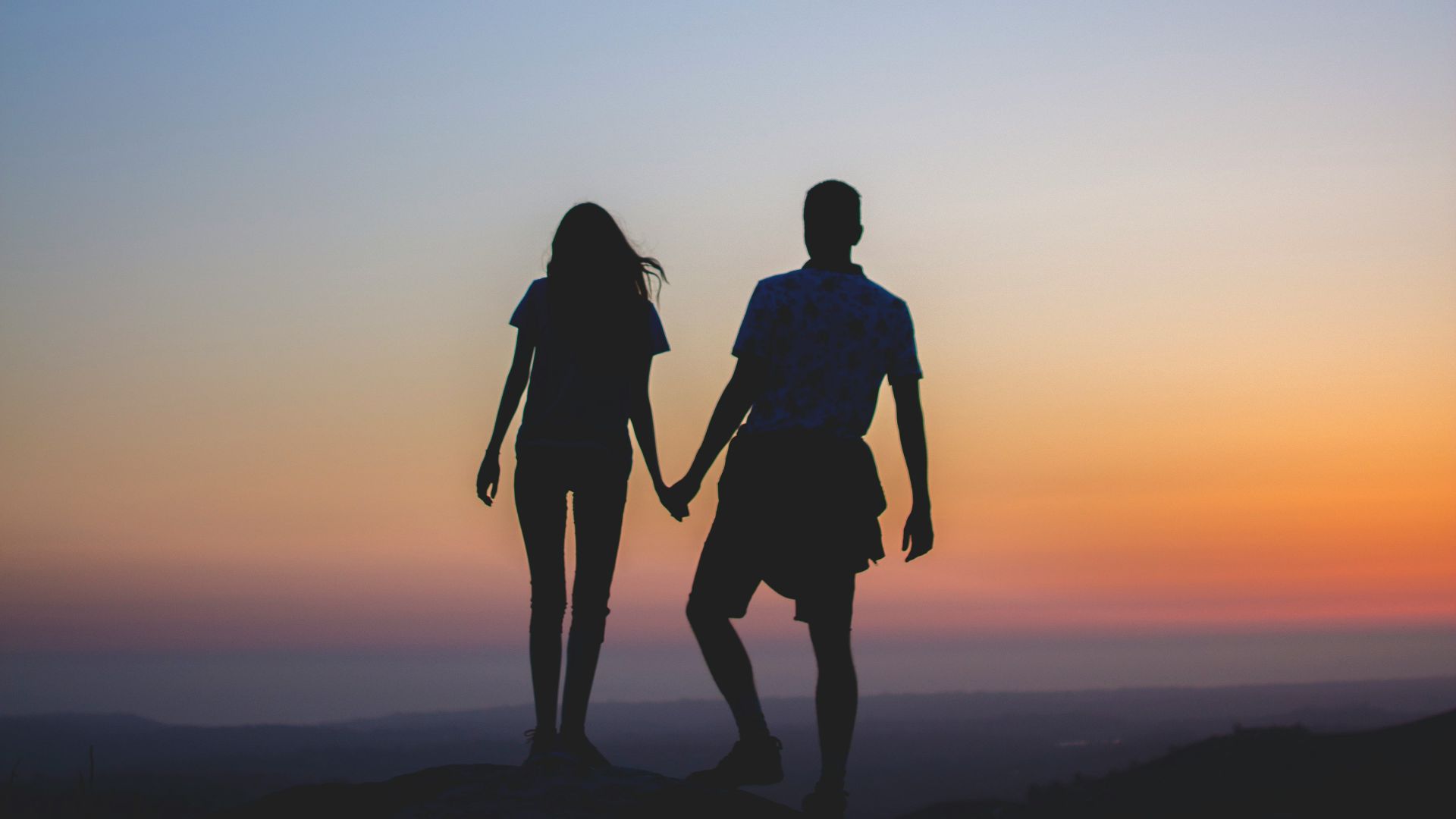 man and woman holding hands in silhouette photography