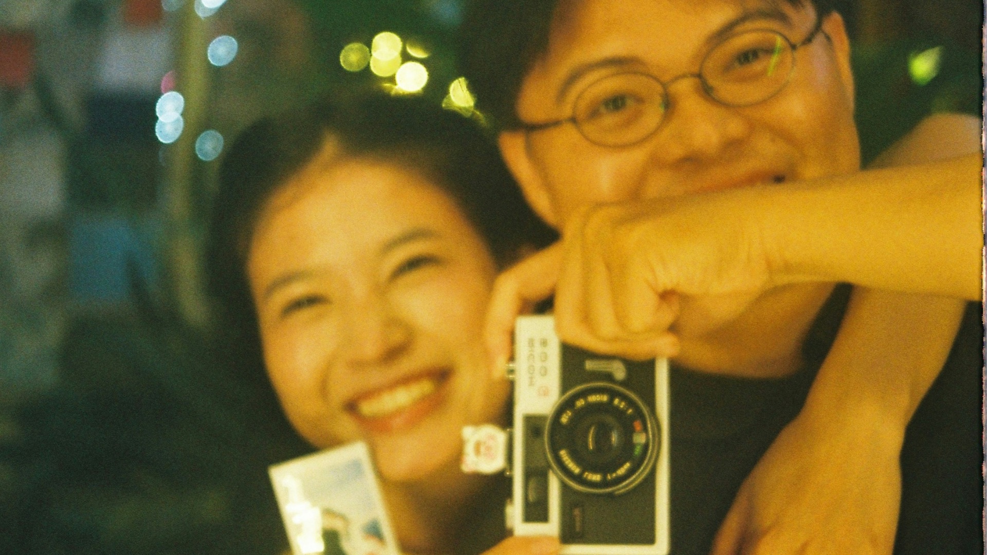 Couple holding instant cameras and smiling