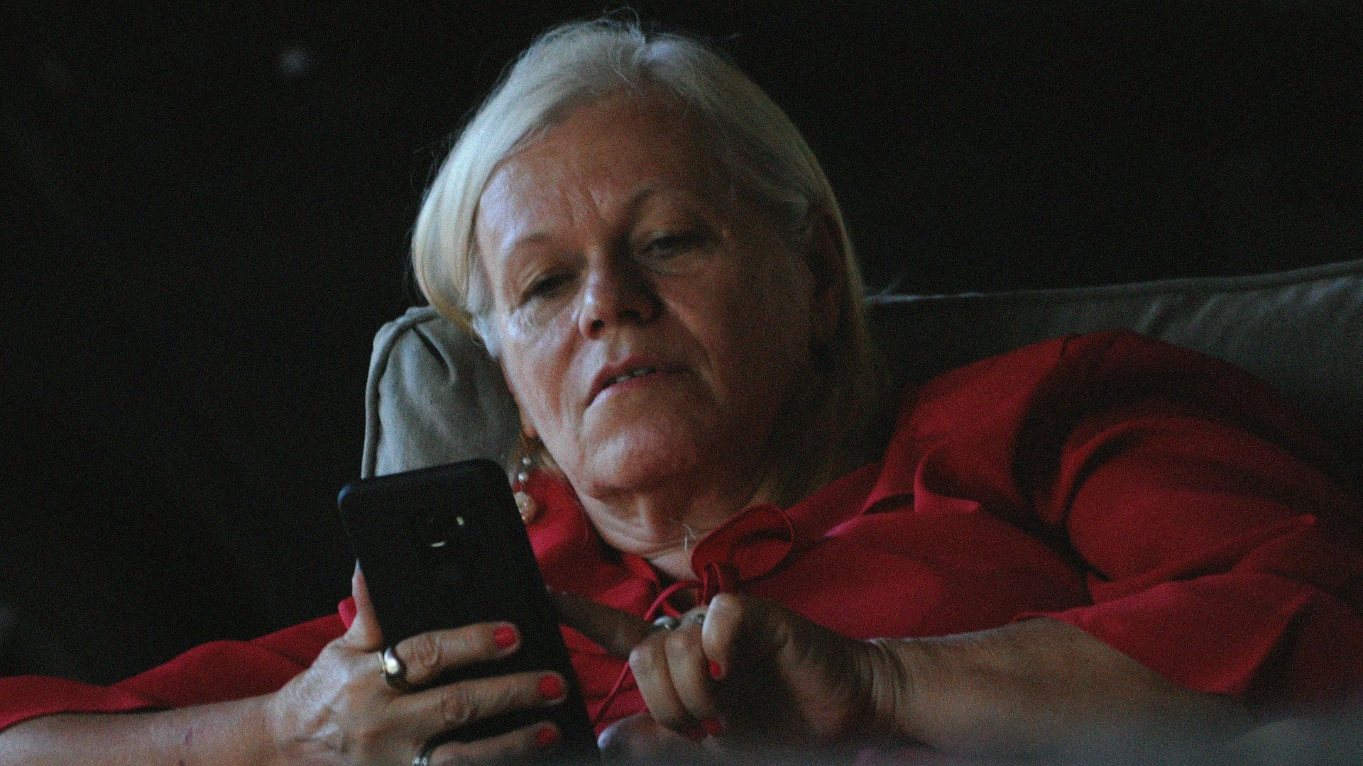 woman in red long sleeve shirt holding black smartphone