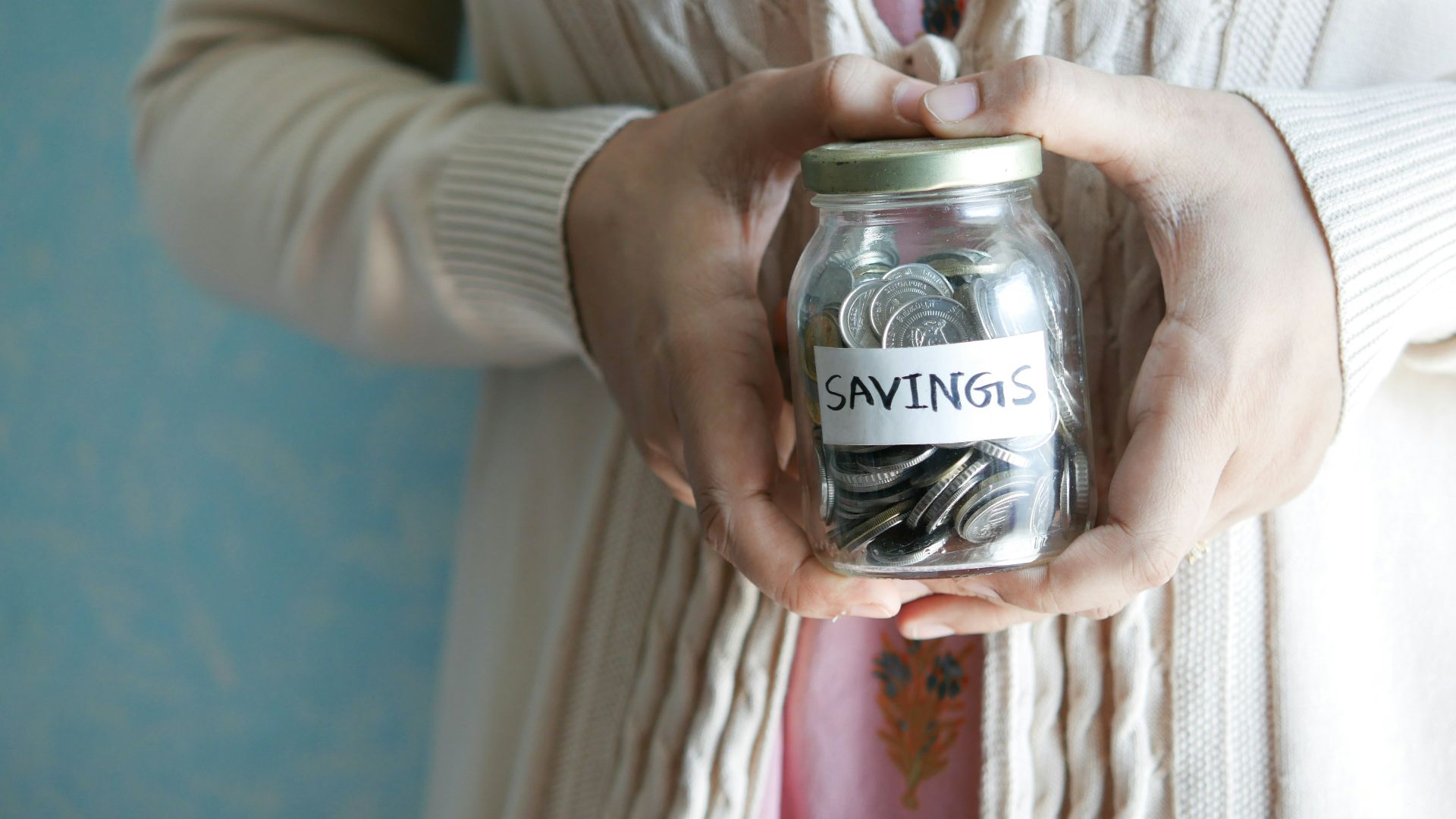 a woman holding a jar with savings written on it
