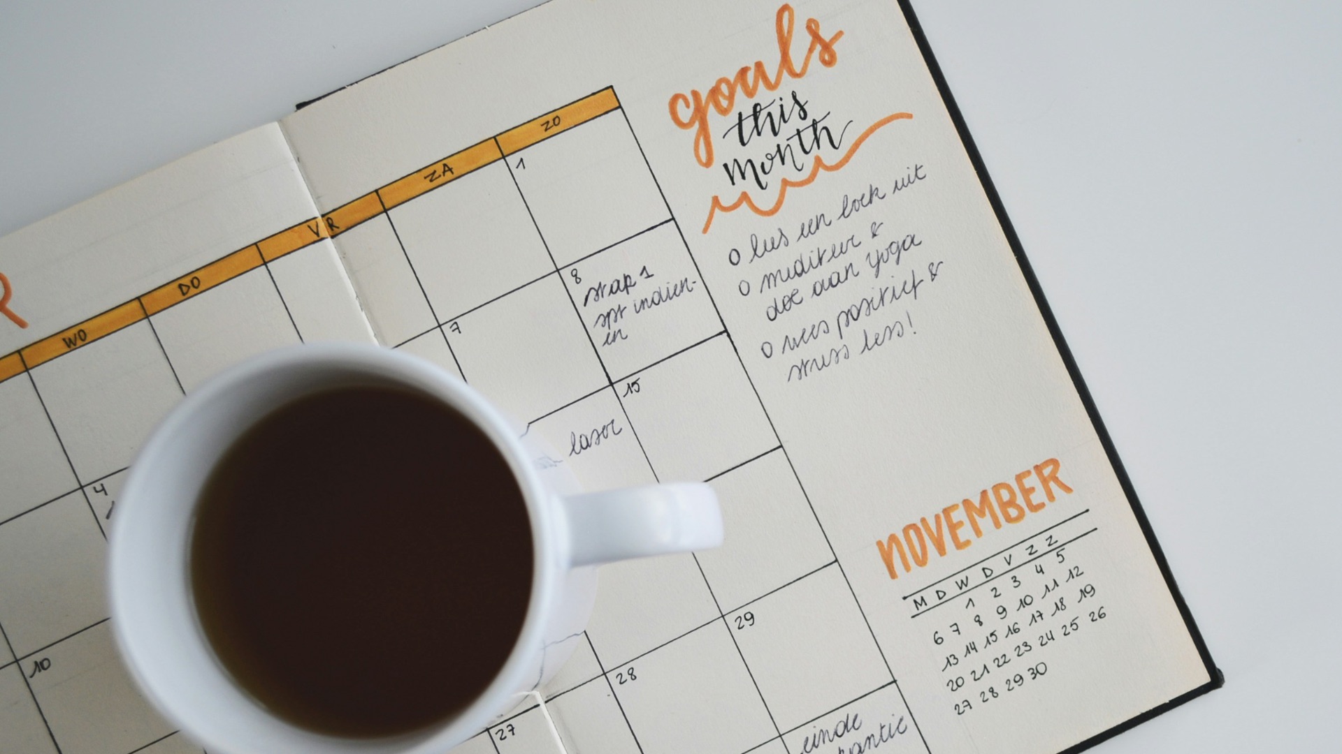 white ceramic mug with coffee on top of a planner