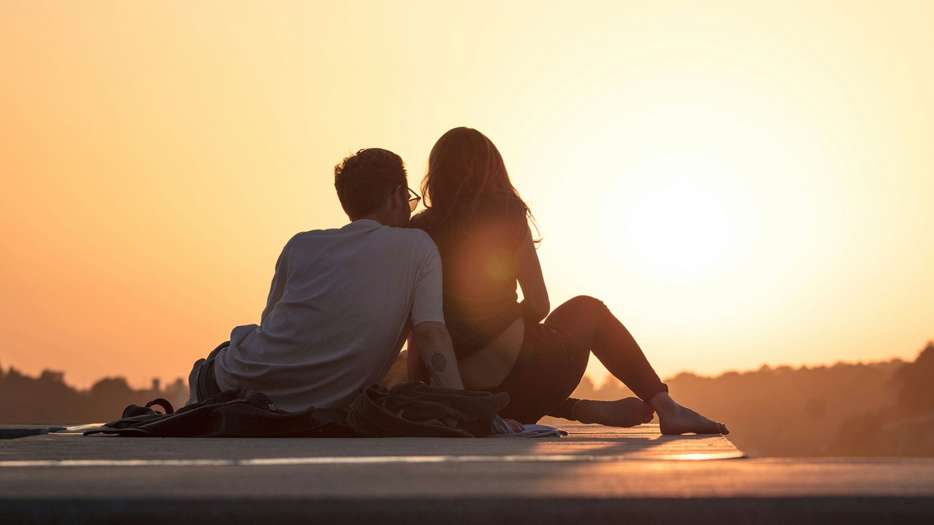 couple sitting near trees during golden hour