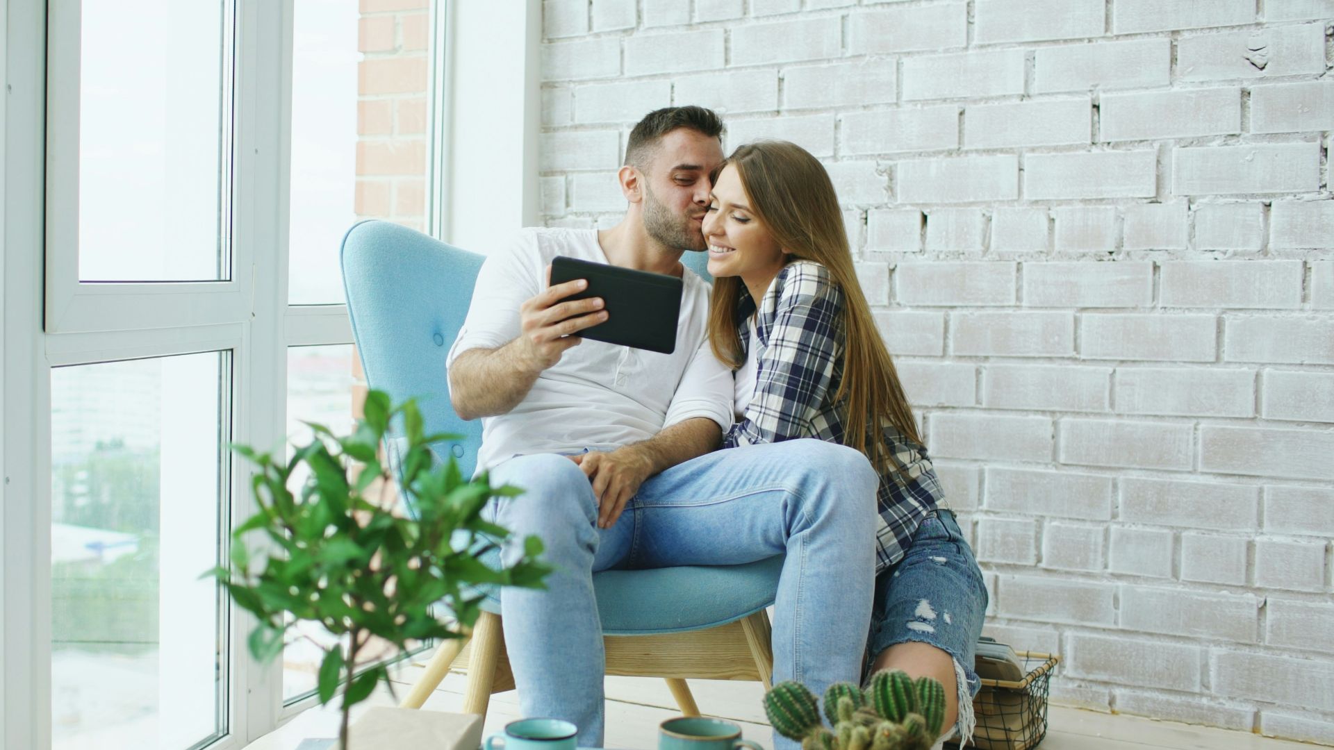 Couple looking at tablet in a bright room.