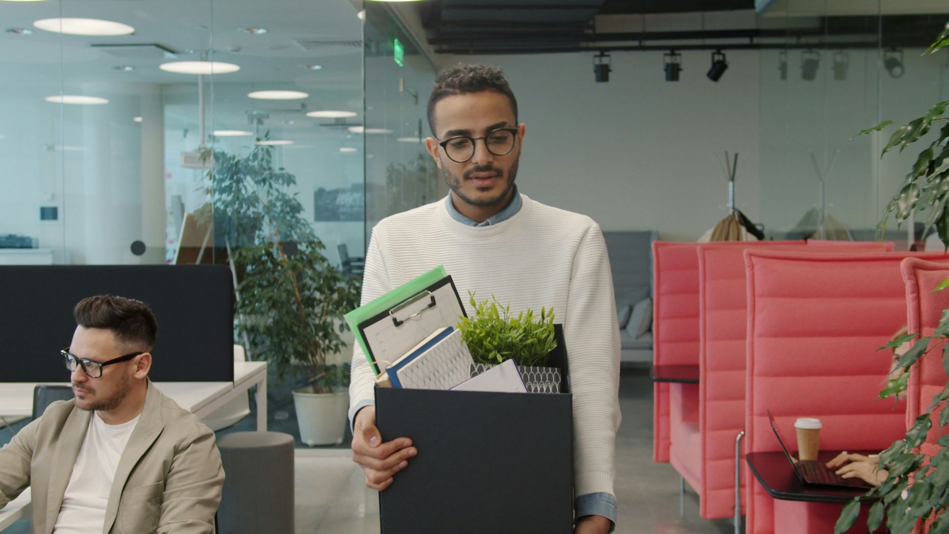 Man carrying box of belongings in modern office