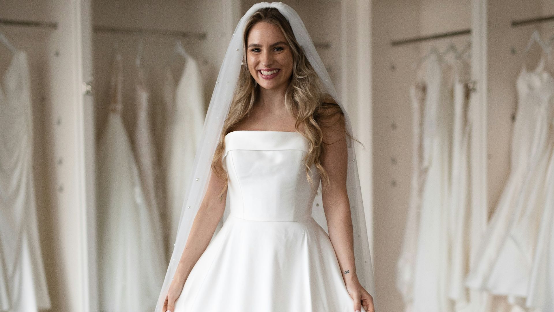 a woman in a wedding dress standing in front of a rack of dresses