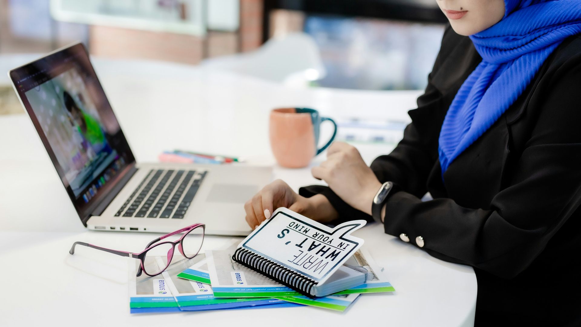 a woman sitting at a table working on a laptop