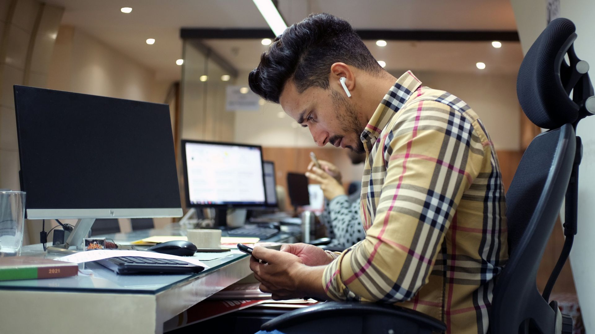 a man sitting at a desk using a cell phone