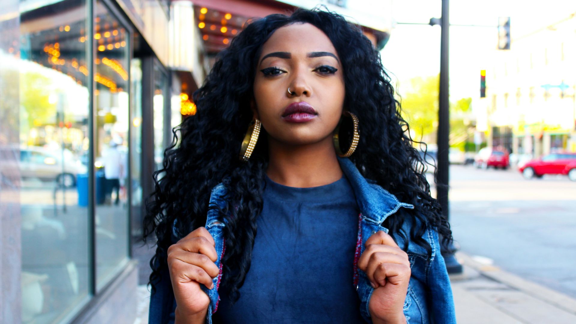 women holding denim jacket near glass window