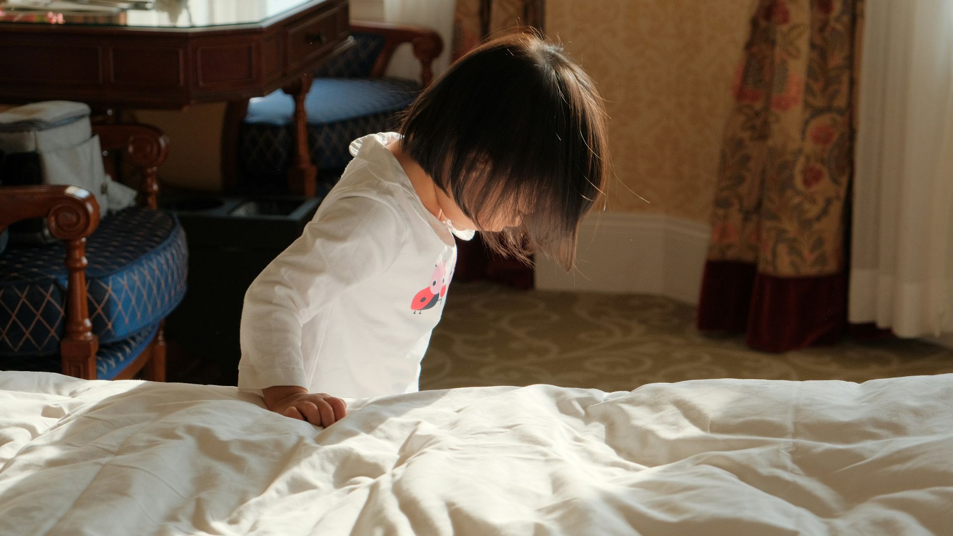 A young child standing on top of a bed