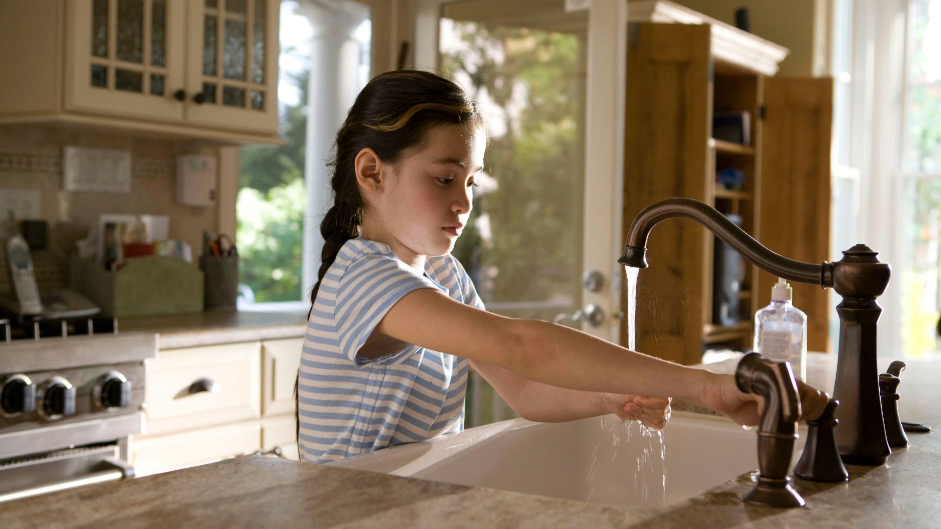 woman in blue and white stripe shirt washing her hands