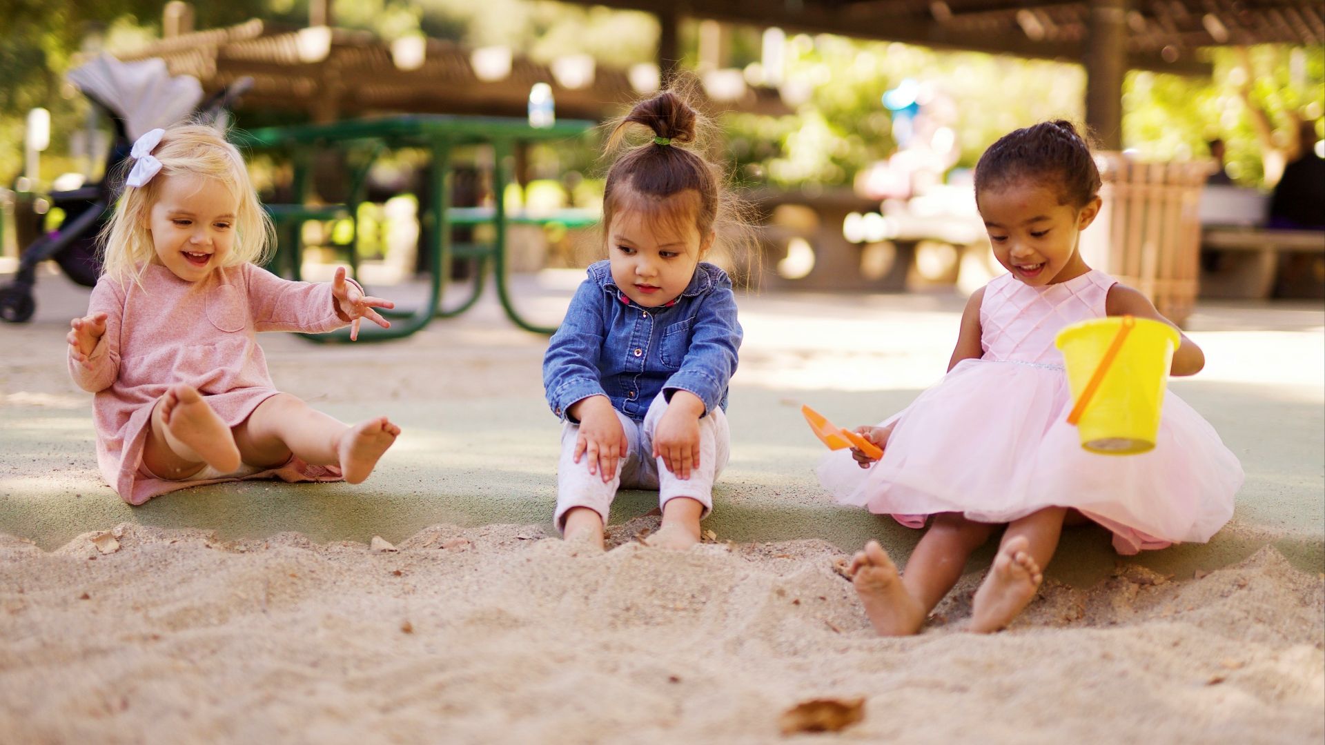 girl in pink dress sitting on brown sand during daytime