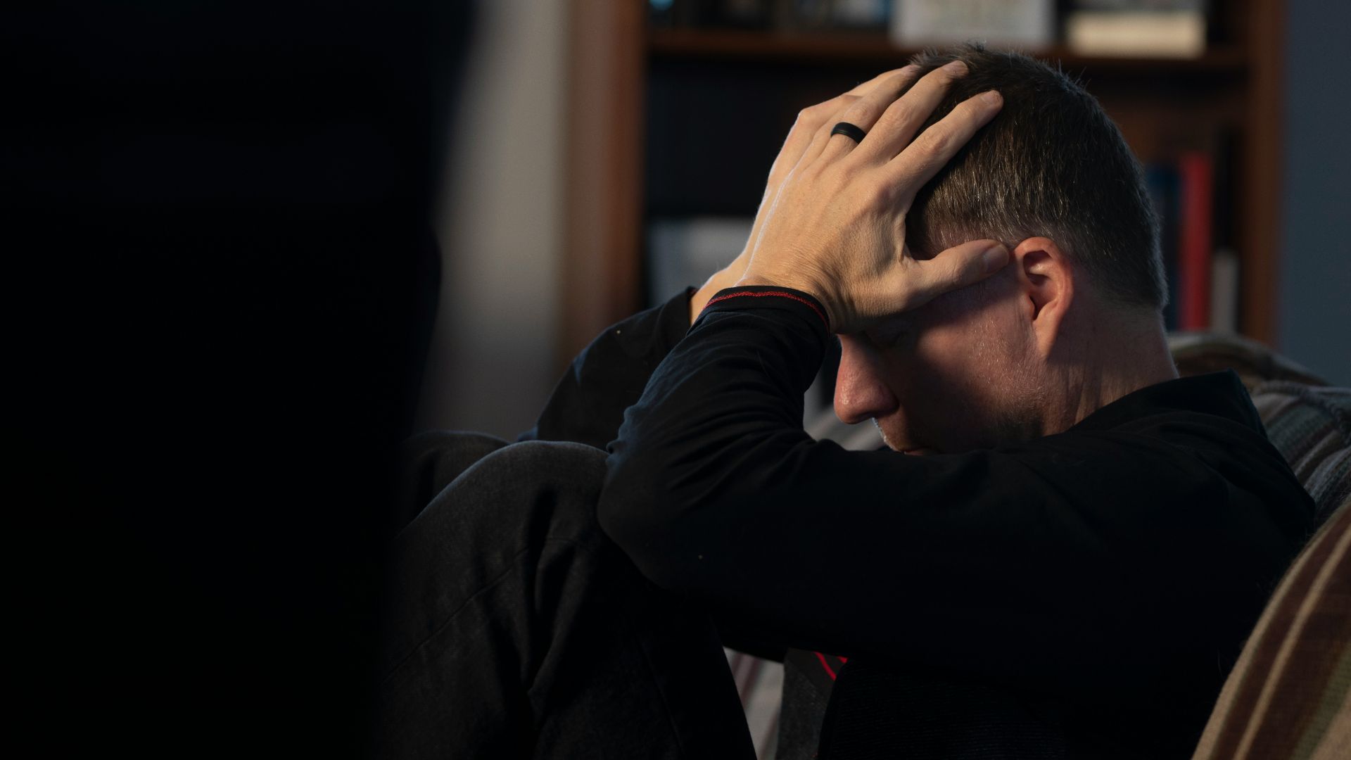 a man sitting on a couch holding his head in his hands
