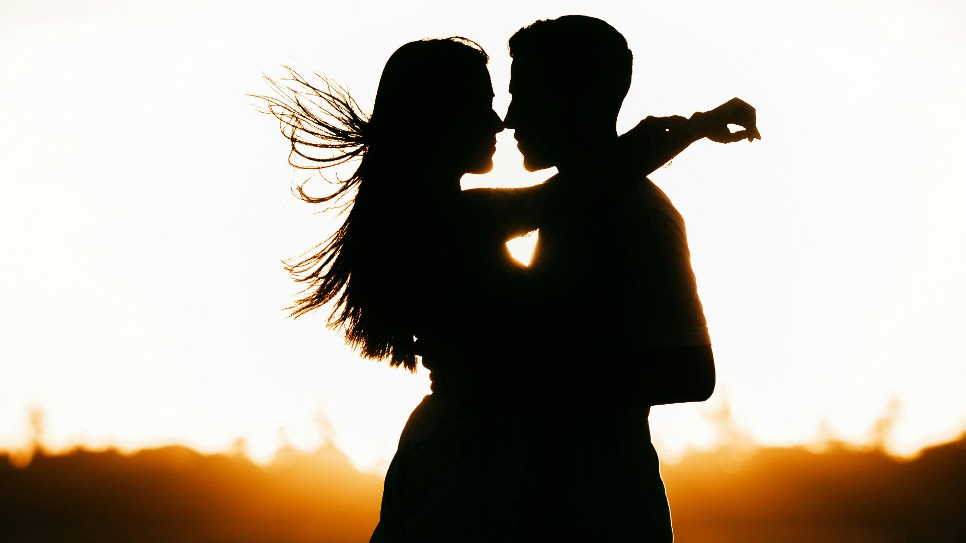 silhouette of woman standing on beach during sunset
