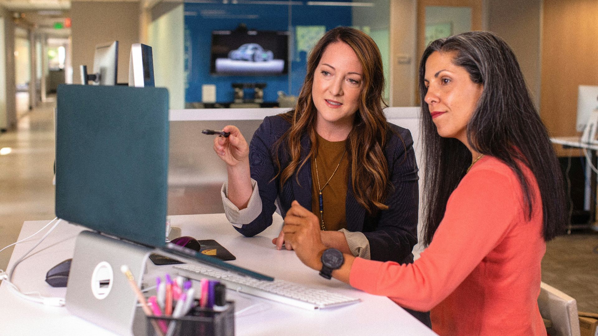 two women sitting at a table looking at a computer screen