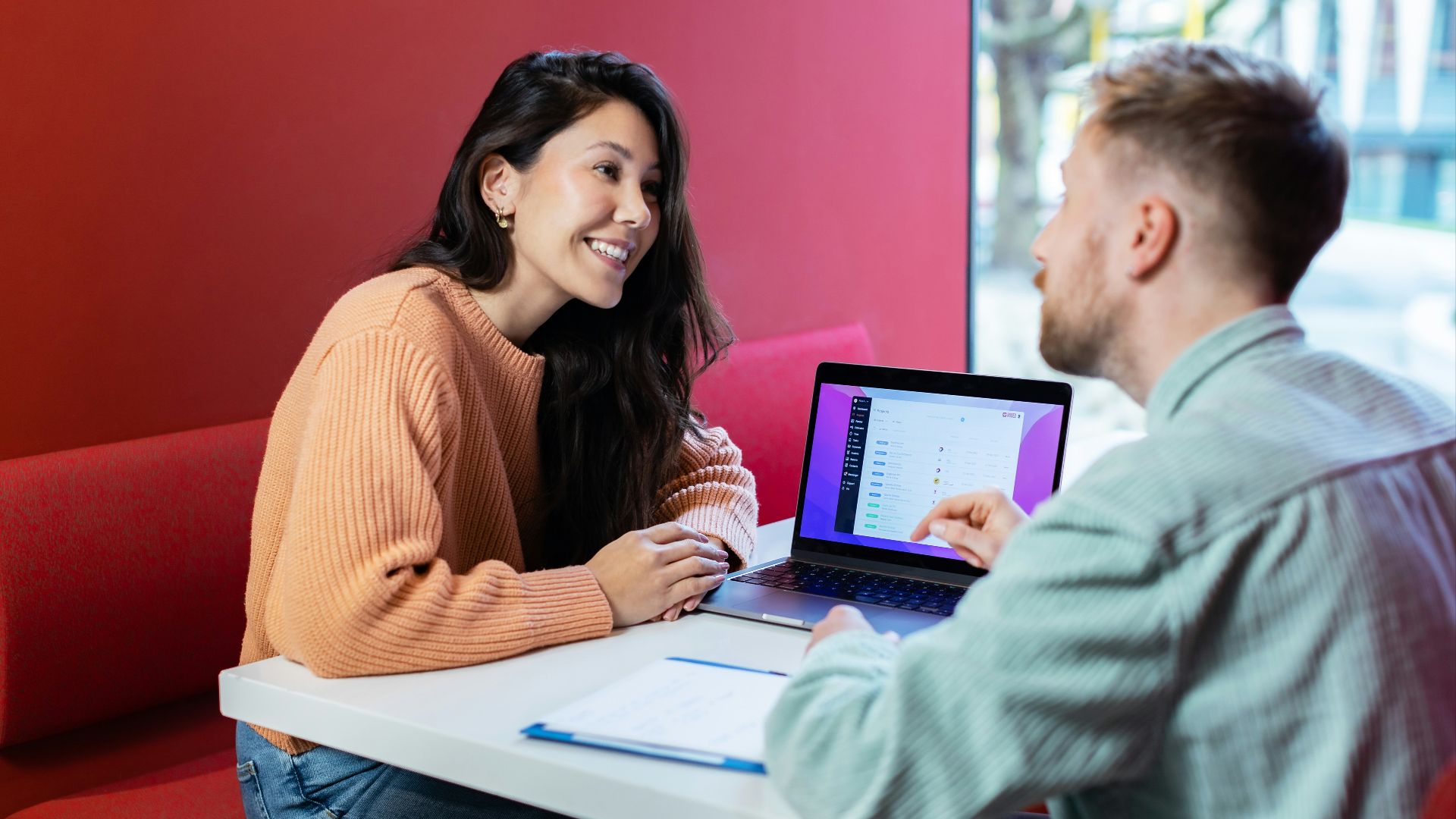 a man and woman sitting at a table with a laptop