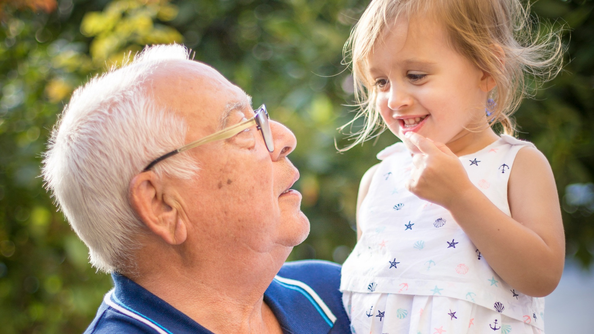 man in blue polo shirt carrying girl in white and pink floral dress